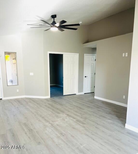 empty room featuring baseboards, wood finished floors, a ceiling fan, and vaulted ceiling