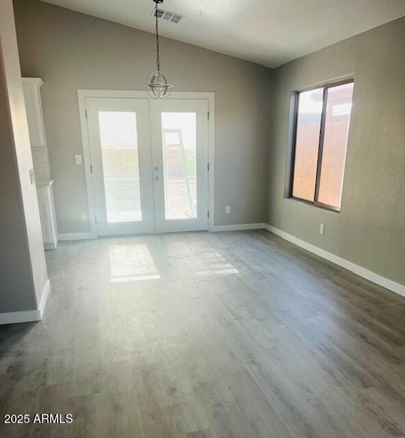 unfurnished dining area featuring lofted ceiling, visible vents, wood finished floors, and baseboards