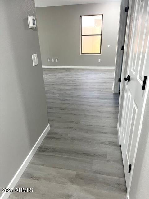 hallway featuring baseboards and wood finished floors