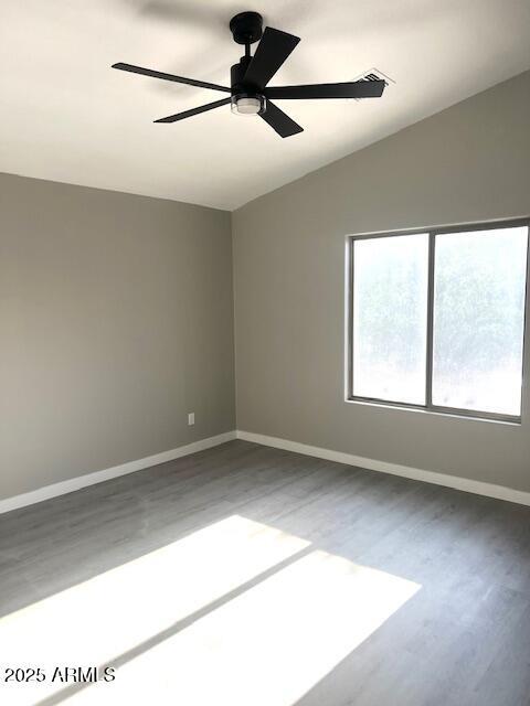 empty room featuring baseboards, wood finished floors, ceiling fan, and lofted ceiling