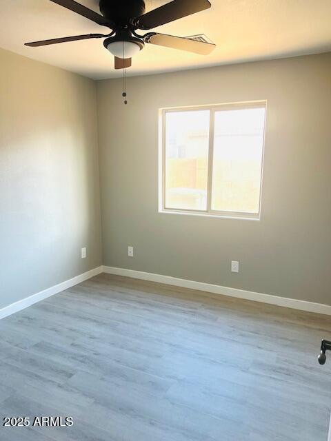 unfurnished room featuring baseboards, wood finished floors, and a ceiling fan
