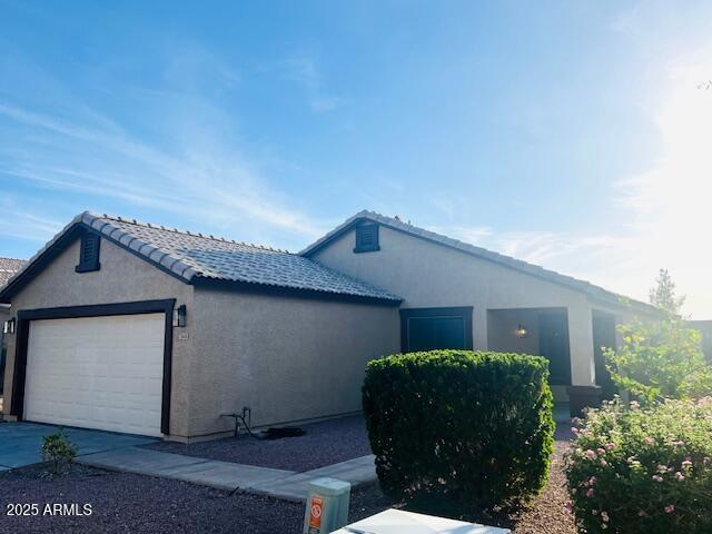 ranch-style house with a garage and stucco siding