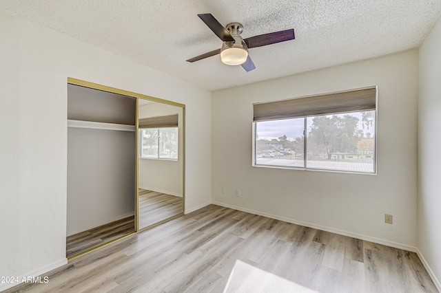 unfurnished bedroom with ceiling fan, a closet, a textured ceiling, and light wood-type flooring