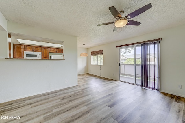 unfurnished living room with ceiling fan, light hardwood / wood-style floors, and a textured ceiling