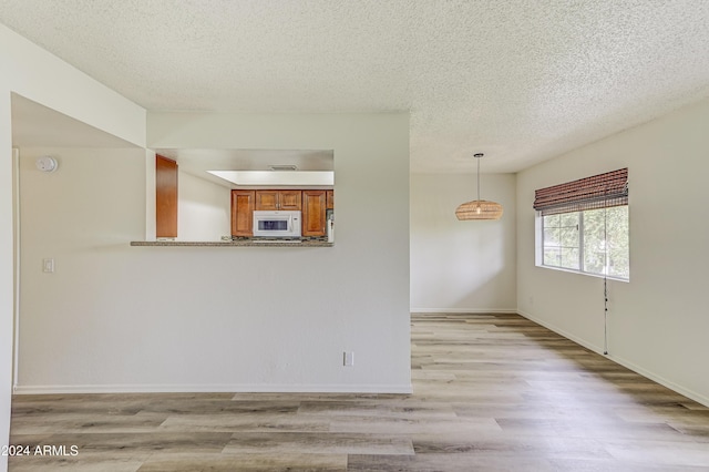 spare room with light hardwood / wood-style floors and a textured ceiling