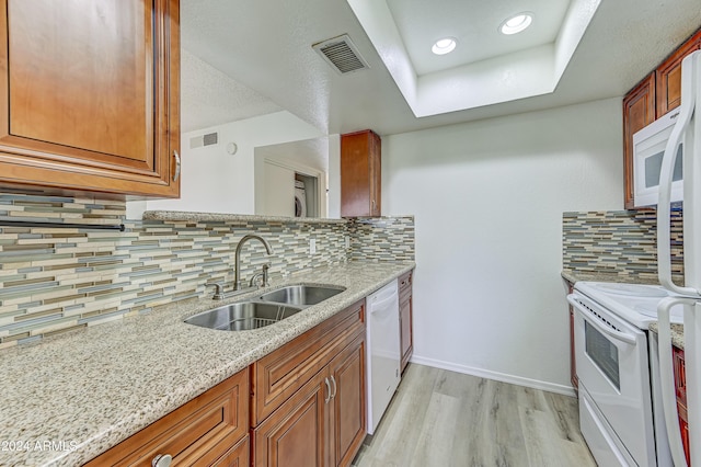 kitchen with tasteful backsplash, light stone counters, sink, and white appliances