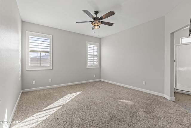 carpeted empty room with ceiling fan and plenty of natural light