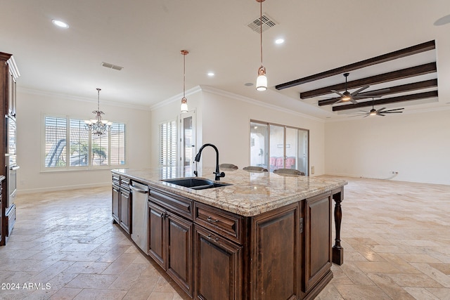 kitchen with a center island with sink, sink, light stone counters, ornamental molding, and decorative light fixtures