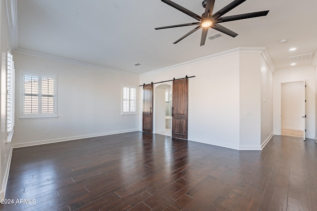 empty room with a barn door, a healthy amount of sunlight, and dark hardwood / wood-style floors