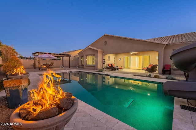 pool at dusk featuring a fire pit and a patio area