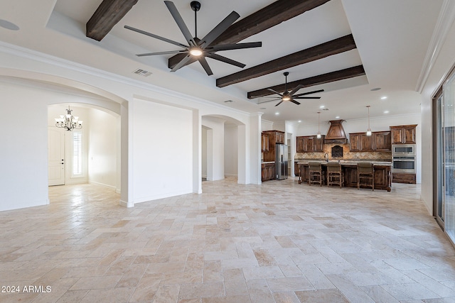 unfurnished living room featuring beamed ceiling, sink, ornamental molding, and ceiling fan with notable chandelier