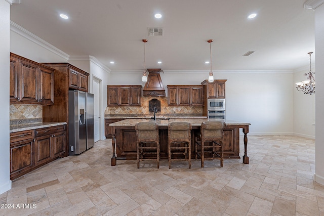 kitchen featuring stainless steel appliances, light stone countertops, backsplash, hanging light fixtures, and an island with sink