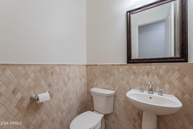 bathroom with toilet and tile walls