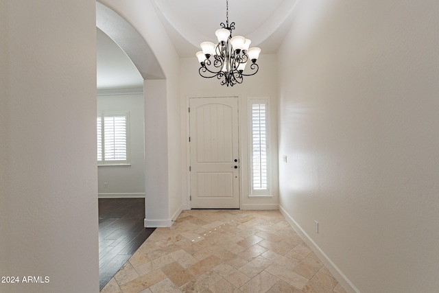 entryway with a wealth of natural light, a chandelier, and light hardwood / wood-style floors