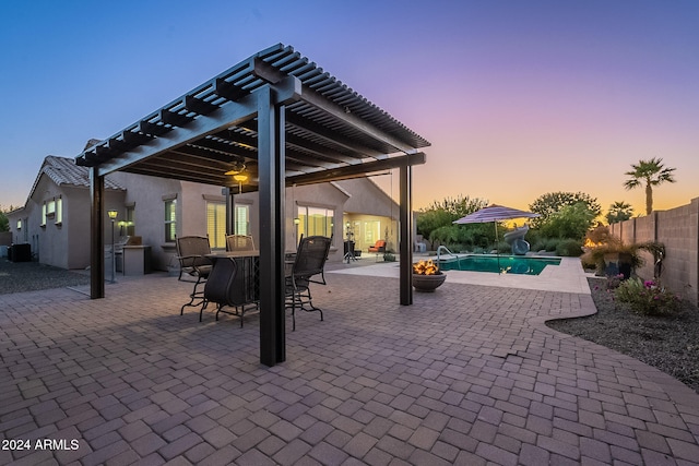 patio terrace at dusk with a fenced in pool and a pergola