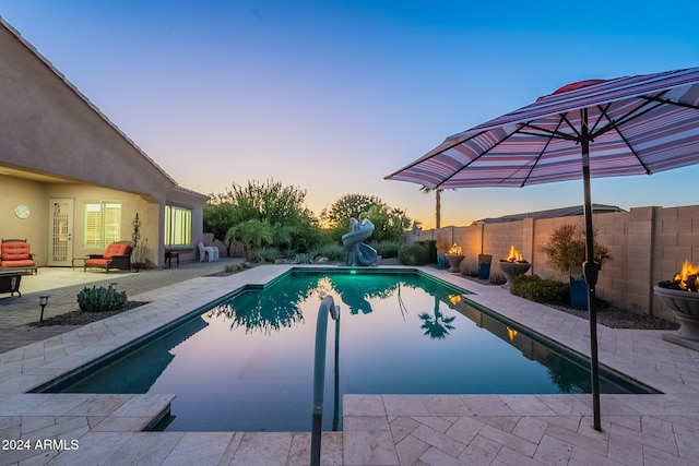 pool at dusk with a water slide and a patio area