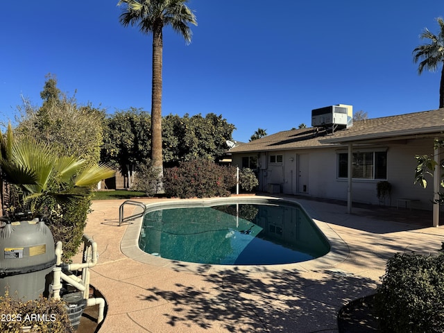 outdoor pool with a patio area and cooling unit