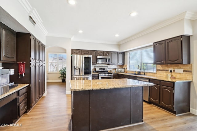 kitchen with stainless steel appliances, a center island, sink, and dark brown cabinetry