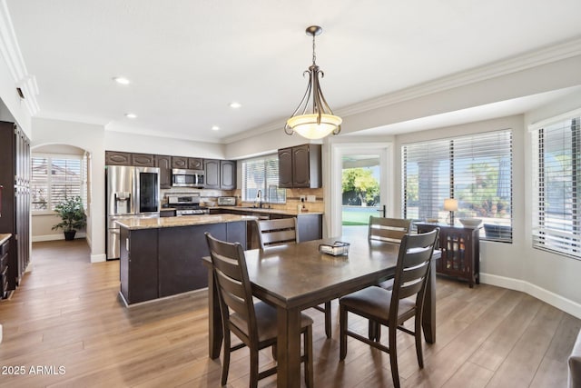 dining space with crown molding, sink, and light hardwood / wood-style floors