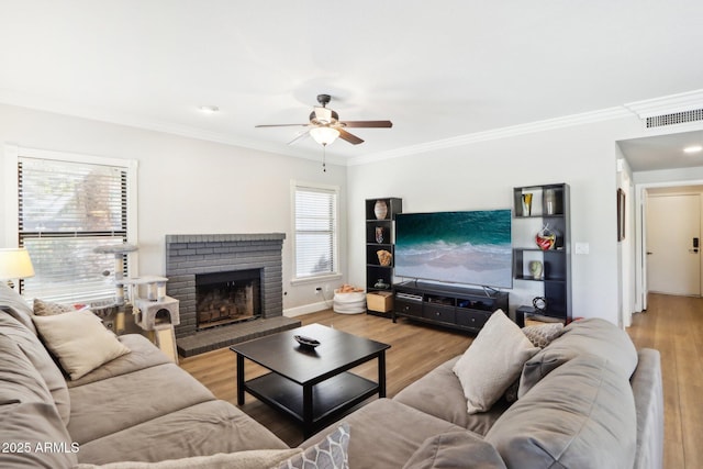 living room with crown molding, ceiling fan, a fireplace, and light hardwood / wood-style flooring