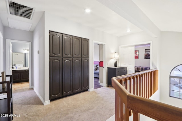 bedroom featuring light colored carpet, beam ceiling, and a closet