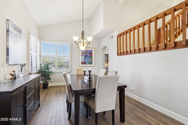 dining area with vaulted ceiling, dark hardwood / wood-style floors, and an inviting chandelier