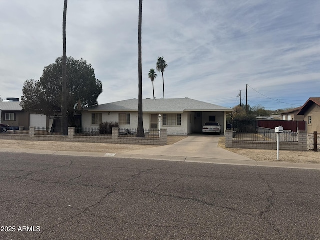 single story home with a fenced front yard, concrete driveway, and a carport