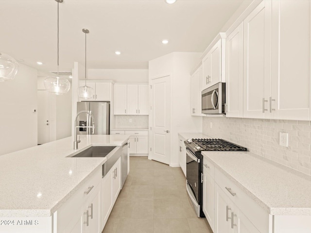 kitchen with white cabinets, decorative light fixtures, an island with sink, and stainless steel appliances