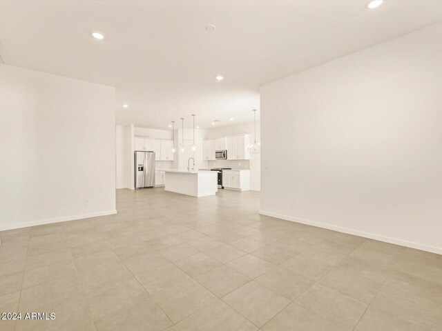 unfurnished living room with light tile patterned floors and sink