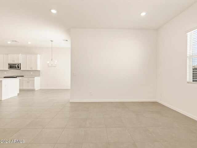 tiled spare room with an inviting chandelier