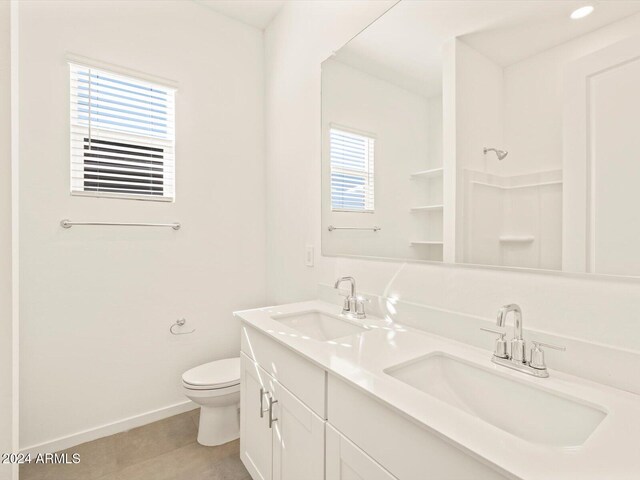 bathroom with toilet, vanity, tile patterned floors, and a healthy amount of sunlight