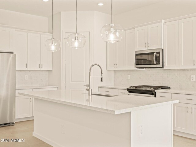 kitchen featuring appliances with stainless steel finishes, hanging light fixtures, sink, and an island with sink