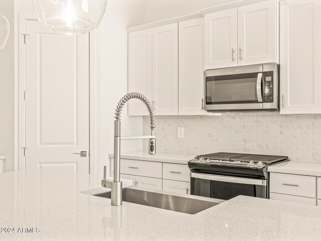 kitchen featuring white cabinets, stainless steel appliances, and light stone countertops