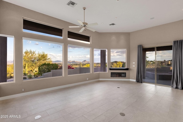 16814 N Boulder Dr, Fountain Hills, AZ 85268 - empty room with ceiling fan, a glass covered fireplace, light tile patterned floors, baseboards, and a towering ceiling