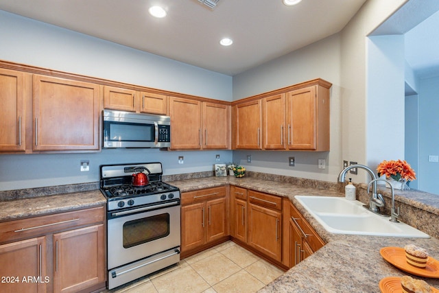 kitchen with appliances with stainless steel finishes, sink, and light tile patterned floors