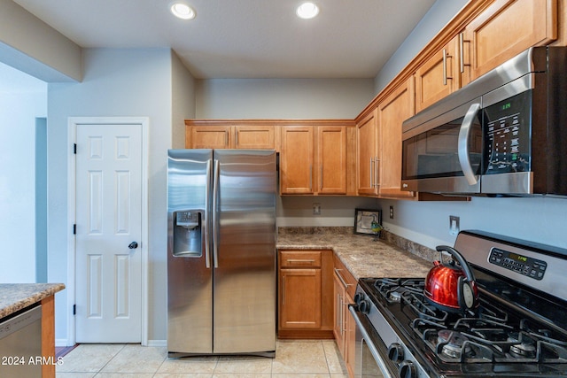 kitchen featuring light tile patterned flooring, light stone counters, and stainless steel appliances