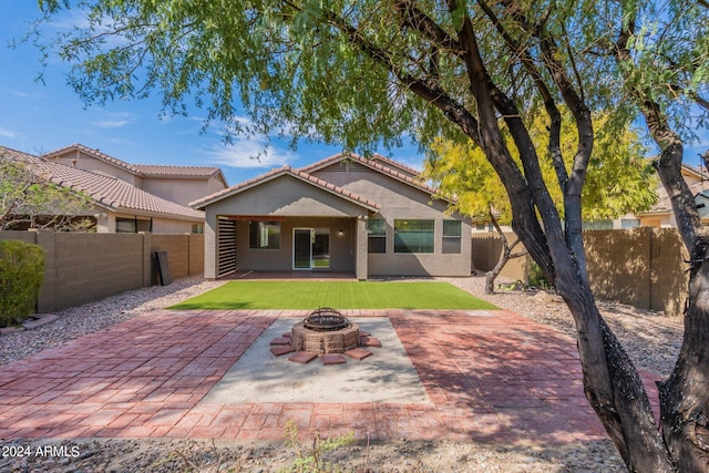 back of house featuring an outdoor fire pit, a patio, and a lawn