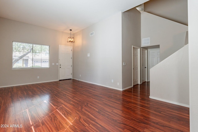 unfurnished room featuring a high ceiling, an inviting chandelier, and dark hardwood / wood-style flooring