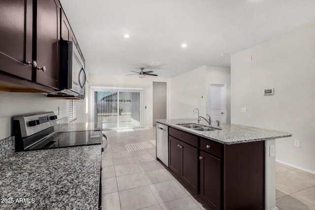 kitchen featuring a center island with sink, appliances with stainless steel finishes, stone counters, sink, and light tile patterned flooring