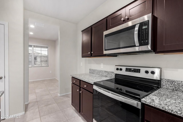 kitchen with stainless steel appliances, light stone countertops, light tile patterned floors, and dark brown cabinetry