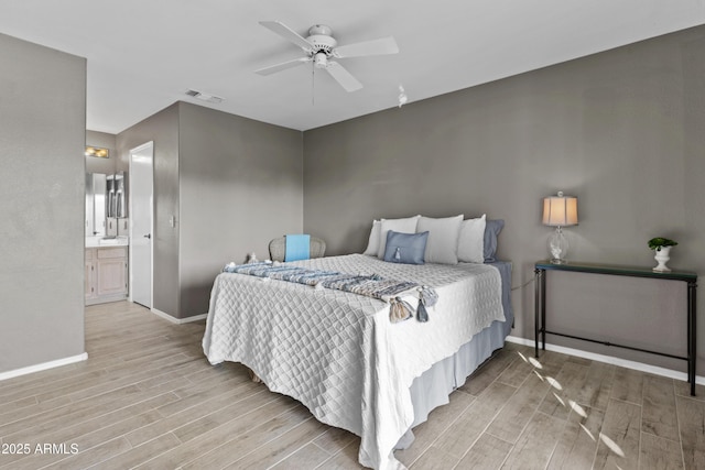 bedroom featuring ceiling fan, light hardwood / wood-style floors, and ensuite bath