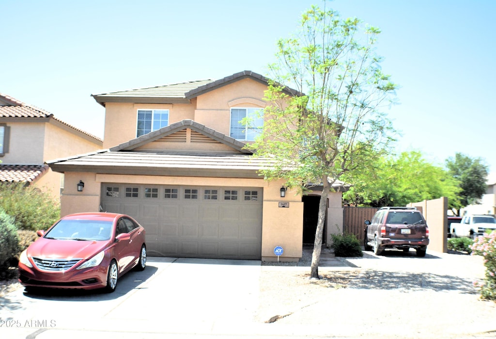 traditional-style house featuring a garage, stucco siding, a tile roof, and concrete driveway