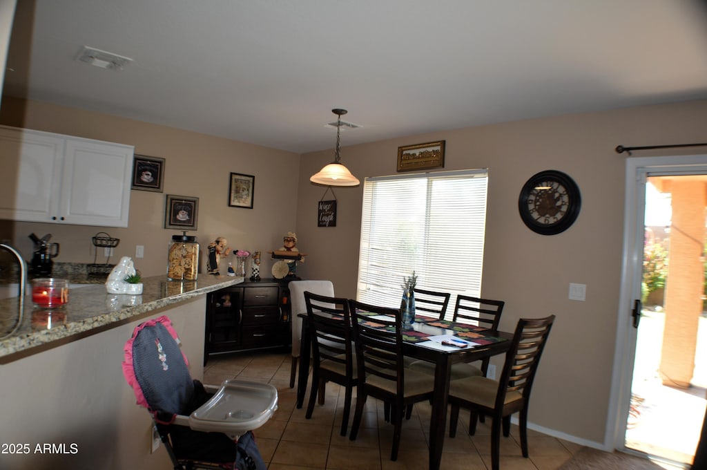 dining space featuring light tile patterned flooring, baseboards, visible vents, and bar area