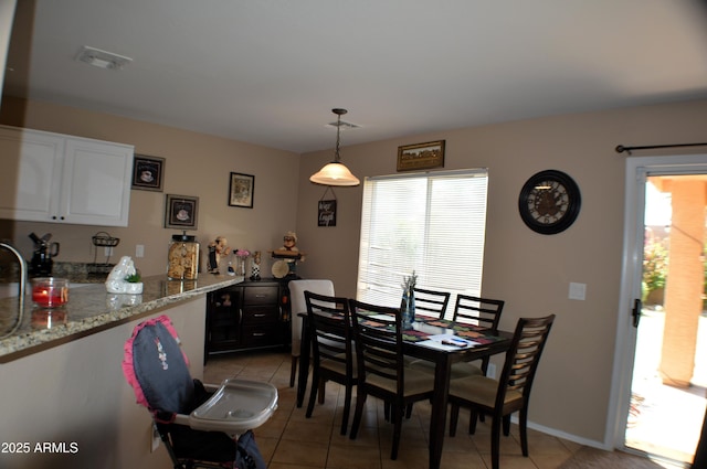 dining space featuring light tile patterned flooring, baseboards, visible vents, and bar area