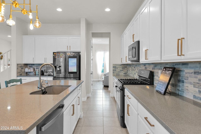 kitchen with appliances with stainless steel finishes, hanging light fixtures, white cabinetry, and sink