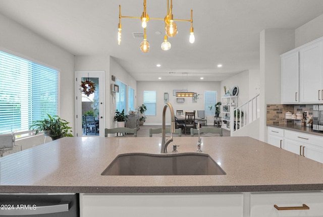 kitchen featuring an island with sink, pendant lighting, sink, and backsplash