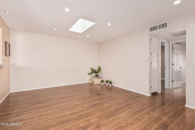 unfurnished room with dark hardwood / wood-style flooring and a skylight