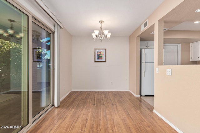 unfurnished dining area with light hardwood / wood-style flooring and a chandelier