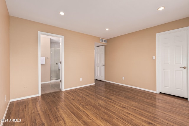 unfurnished bedroom with connected bathroom and dark hardwood / wood-style flooring