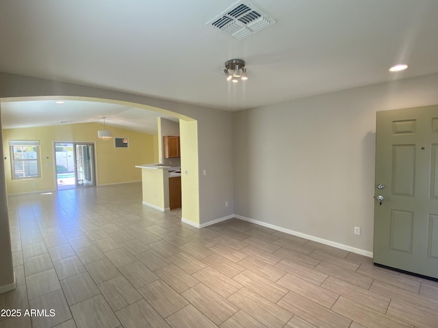 10817 W Wilshire Dr, Avondale, AZ 85392 - unfurnished living room with visible vents, baseboards, wood tiled floor, arched walkways, and vaulted ceiling